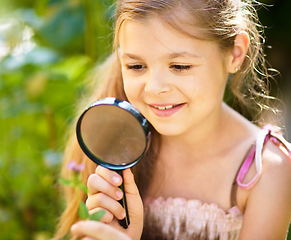 Image showing Young girl is looking at flower through magnifier