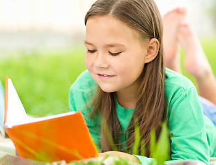 Image showing Little girl is reading a book outdoors