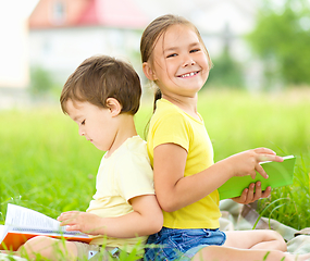 Image showing Little girl and boy are reading books outdoors