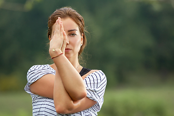 Image showing Young beautiful woman doing yoga exercise in green park. Healthy lifestyle and fitness concept.