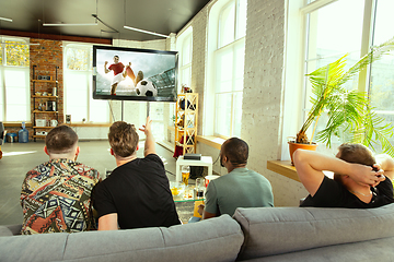 Image showing Group of friends watching football or soccer game on TV at home