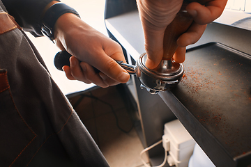 Image showing Stylish black espresso making machine, shooted in cafe. Close-up shot of barista hands