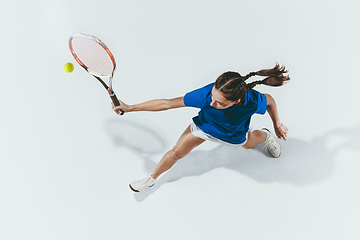 Image showing Young woman in blue shirt playing tennis. Youth, flexibility, power and energy.