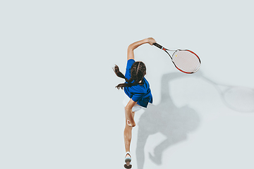 Image showing Young woman in blue shirt playing tennis. Youth, flexibility, power and energy.