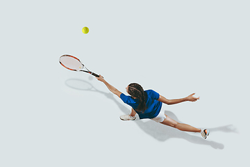 Image showing Young woman in blue shirt playing tennis. Youth, flexibility, power and energy.