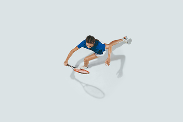 Image showing Young woman in blue shirt playing tennis. Youth, flexibility, power and energy.