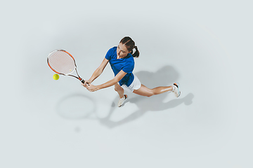 Image showing Young woman in blue shirt playing tennis. Youth, flexibility, power and energy.