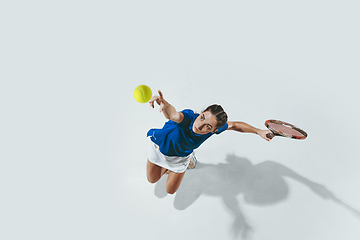 Image showing Young woman in blue shirt playing tennis. Youth, flexibility, power and energy.