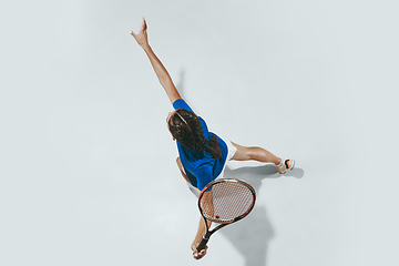 Image showing Young woman in blue shirt playing tennis. Youth, flexibility, power and energy.