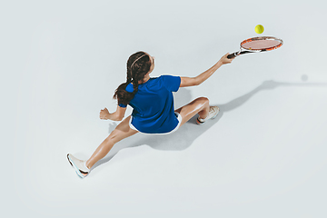 Image showing Young woman in blue shirt playing tennis. Youth, flexibility, power and energy.