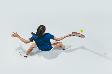 Image showing Young woman in blue shirt playing tennis. Youth, flexibility, power and energy.