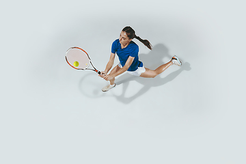 Image showing Young woman in blue shirt playing tennis. Youth, flexibility, power and energy.