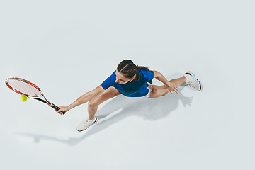 Image showing Young woman in blue shirt playing tennis. Youth, flexibility, power and energy.