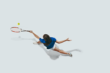 Image showing Young woman in blue shirt playing tennis. Youth, flexibility, power and energy.