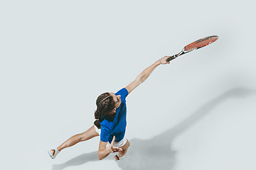 Image showing Young woman in blue shirt playing tennis. Youth, flexibility, power and energy.