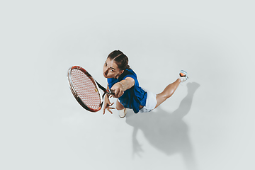 Image showing Young woman in blue shirt playing tennis. Youth, flexibility, power and energy.