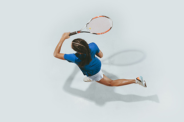 Image showing Young woman in blue shirt playing tennis. Youth, flexibility, power and energy.