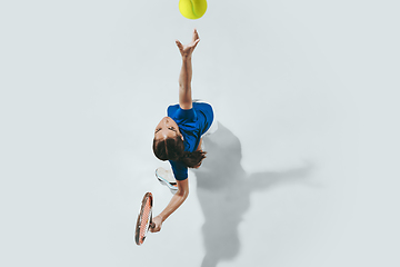 Image showing Young woman in blue shirt playing tennis. Youth, flexibility, power and energy.