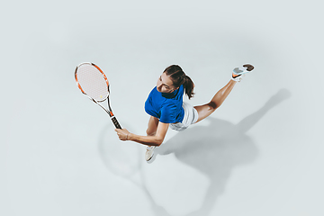 Image showing Young woman in blue shirt playing tennis. Youth, flexibility, power and energy.