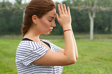 Image showing Young beautiful woman doing yoga exercise in green park. Healthy lifestyle and fitness concept.