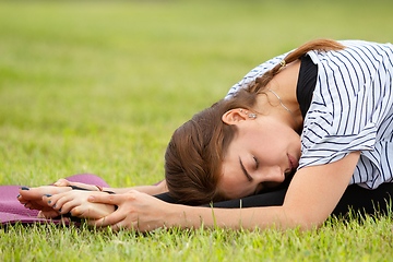 Image showing Young beautiful woman doing yoga exercise in green park. Healthy lifestyle and fitness concept.