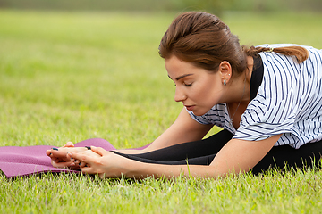 Image showing Young beautiful woman doing yoga exercise in green park. Healthy lifestyle and fitness concept.