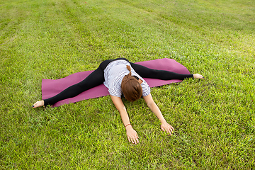 Image showing Young beautiful woman doing yoga exercise in green park. Healthy lifestyle and fitness concept.