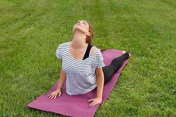 Image showing Young beautiful woman doing yoga exercise in green park. Healthy lifestyle and fitness concept.