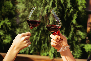 Image showing People clinking glasses with wine on the summer terrace of cafe or restaurant. Close up shot, lifestyle.