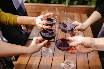 Image showing People clinking glasses with wine on the summer terrace of cafe or restaurant. Close up shot, lifestyle.