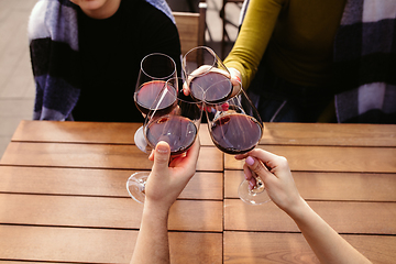 Image showing People clinking glasses with wine on the summer terrace of cafe or restaurant. Close up shot, lifestyle.