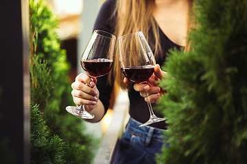 Image showing People clinking glasses with wine on the summer terrace of cafe or restaurant. Close up shot, lifestyle.