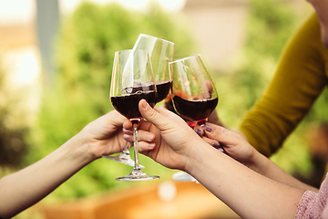 Image showing People clinking glasses with wine on the summer terrace of cafe or restaurant. Close up shot, lifestyle.