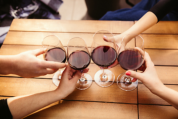 Image showing People clinking glasses with wine on the summer terrace of cafe or restaurant. Close up shot, lifestyle.