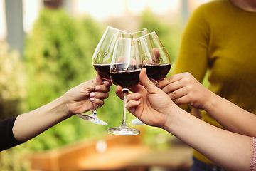 Image showing People clinking glasses with wine on the summer terrace of cafe or restaurant. Close up shot, lifestyle.