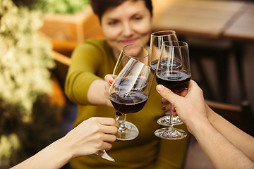 Image showing People clinking glasses with wine on the summer terrace of cafe or restaurant. Close up shot, lifestyle.