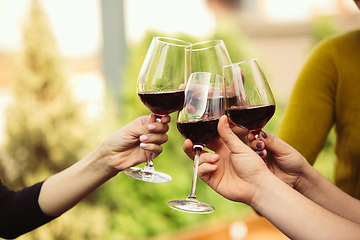 Image showing People clinking glasses with wine on the summer terrace of cafe or restaurant. Close up shot, lifestyle.