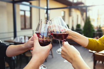 Image showing People clinking glasses with wine on the summer terrace of cafe or restaurant. Close up shot, lifestyle.