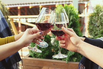 Image showing People clinking glasses with wine on the summer terrace of cafe or restaurant. Close up shot, lifestyle.