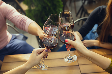 Image showing People clinking glasses with wine on the summer terrace of cafe or restaurant. Close up shot, lifestyle.