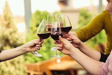 Image showing People clinking glasses with wine on the summer terrace of cafe or restaurant. Close up shot, lifestyle.