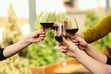 Image showing People clinking glasses with wine on the summer terrace of cafe or restaurant. Close up shot, lifestyle.