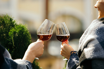 Image showing People clinking glasses with wine on the summer terrace of cafe or restaurant. Close up shot, lifestyle.