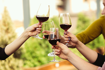 Image showing People clinking glasses with wine on the summer terrace of cafe or restaurant. Close up shot, lifestyle.