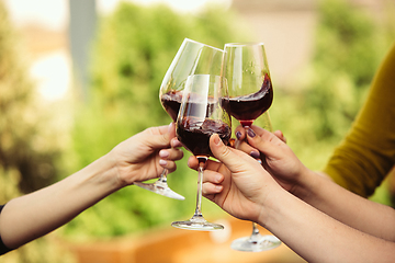 Image showing People clinking glasses with wine on the summer terrace of cafe or restaurant. Close up shot, lifestyle.