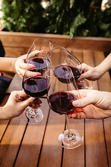 Image showing People clinking glasses with wine on the summer terrace of cafe or restaurant. Close up shot, lifestyle.