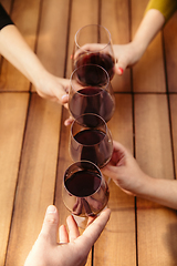 Image showing People clinking glasses with wine on the summer terrace of cafe or restaurant. Close up shot, lifestyle.