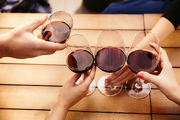 Image showing People clinking glasses with wine on the summer terrace of cafe or restaurant. Close up shot, lifestyle.