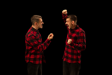 Image showing Young handsome man arguing with himself on black studio background.