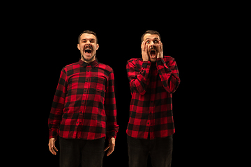 Image showing Young handsome man arguing with himself on black studio background.